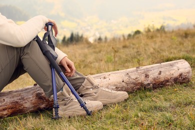 Woman with trekking poles resting during hike in mountains, closeup. Space for text