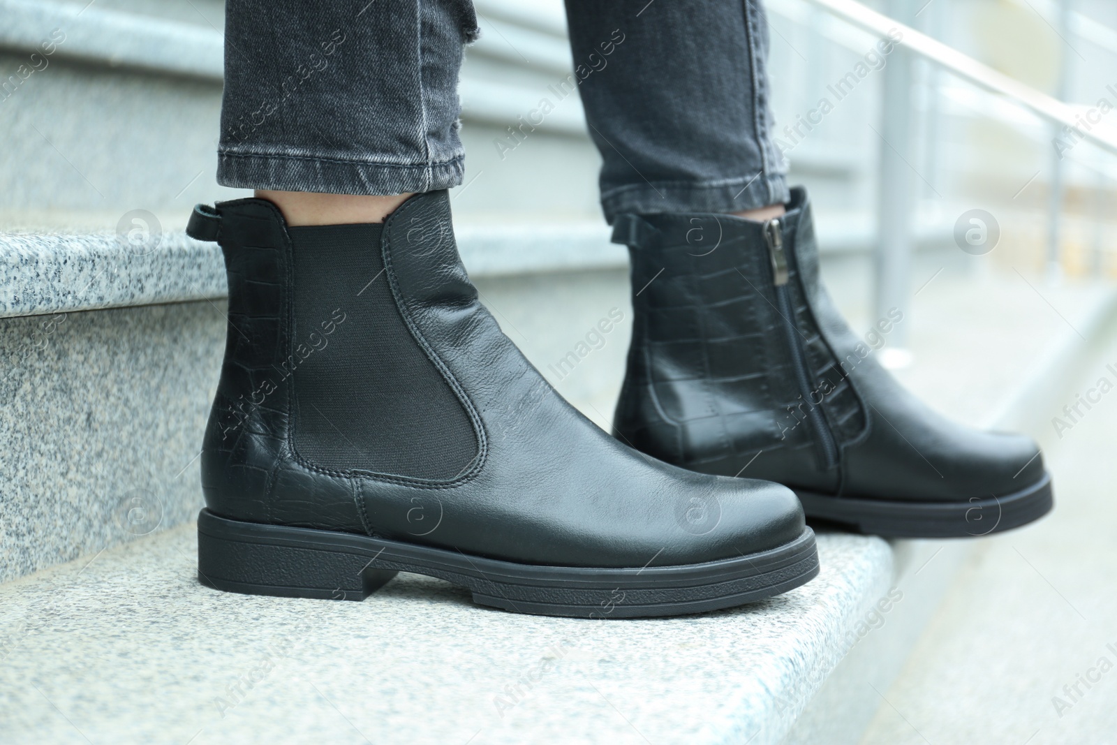 Photo of Woman in stylish boots on stairs outdoors, closeup