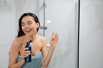 Photo of Young woman with bottle of gel singing while taking shower. Space for text