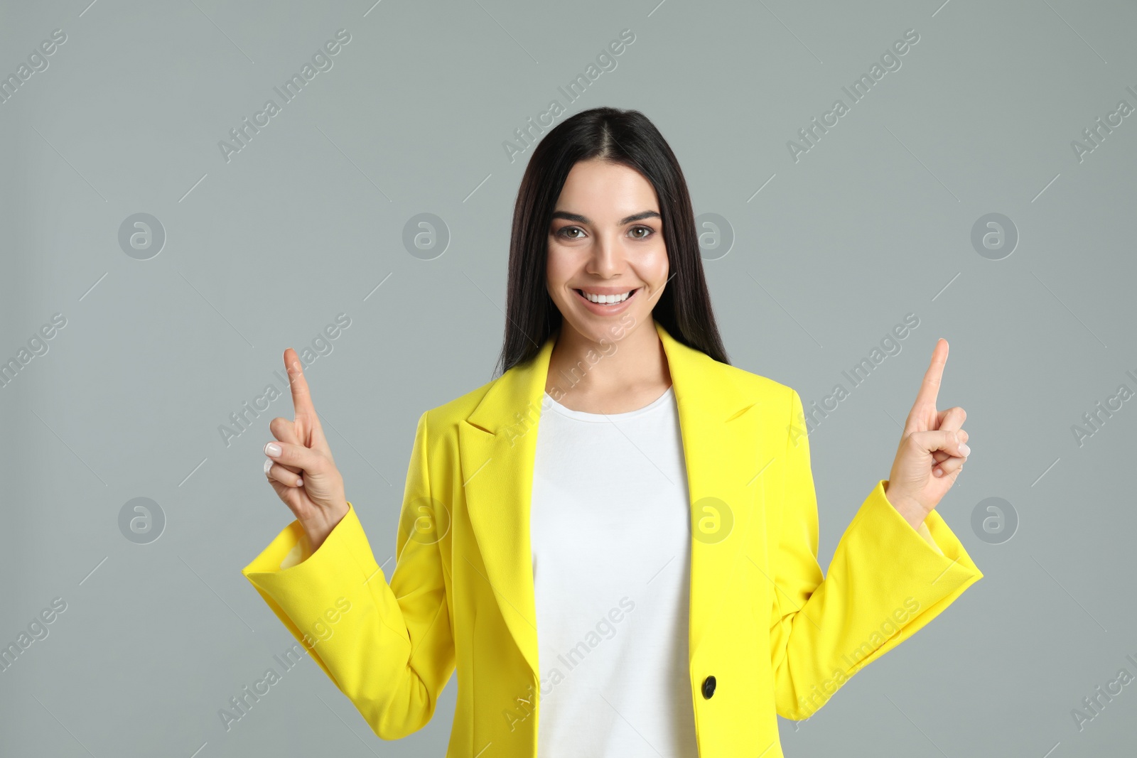 Photo of Woman showing number two with her hands on grey background