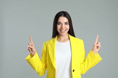 Woman showing number two with her hands on grey background