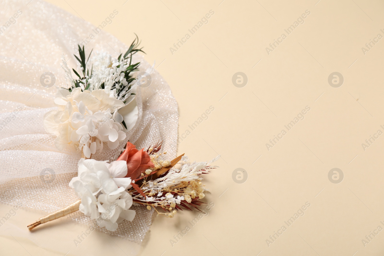 Photo of Stylish boutonniere and white fabric on beige background, space for text