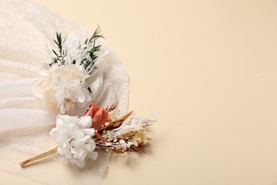 Stylish boutonniere and white fabric on beige background, space for text