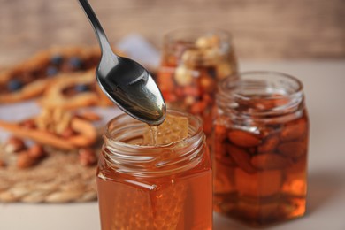 Photo of Spoon of honey above glass jar, closeup. Space for text