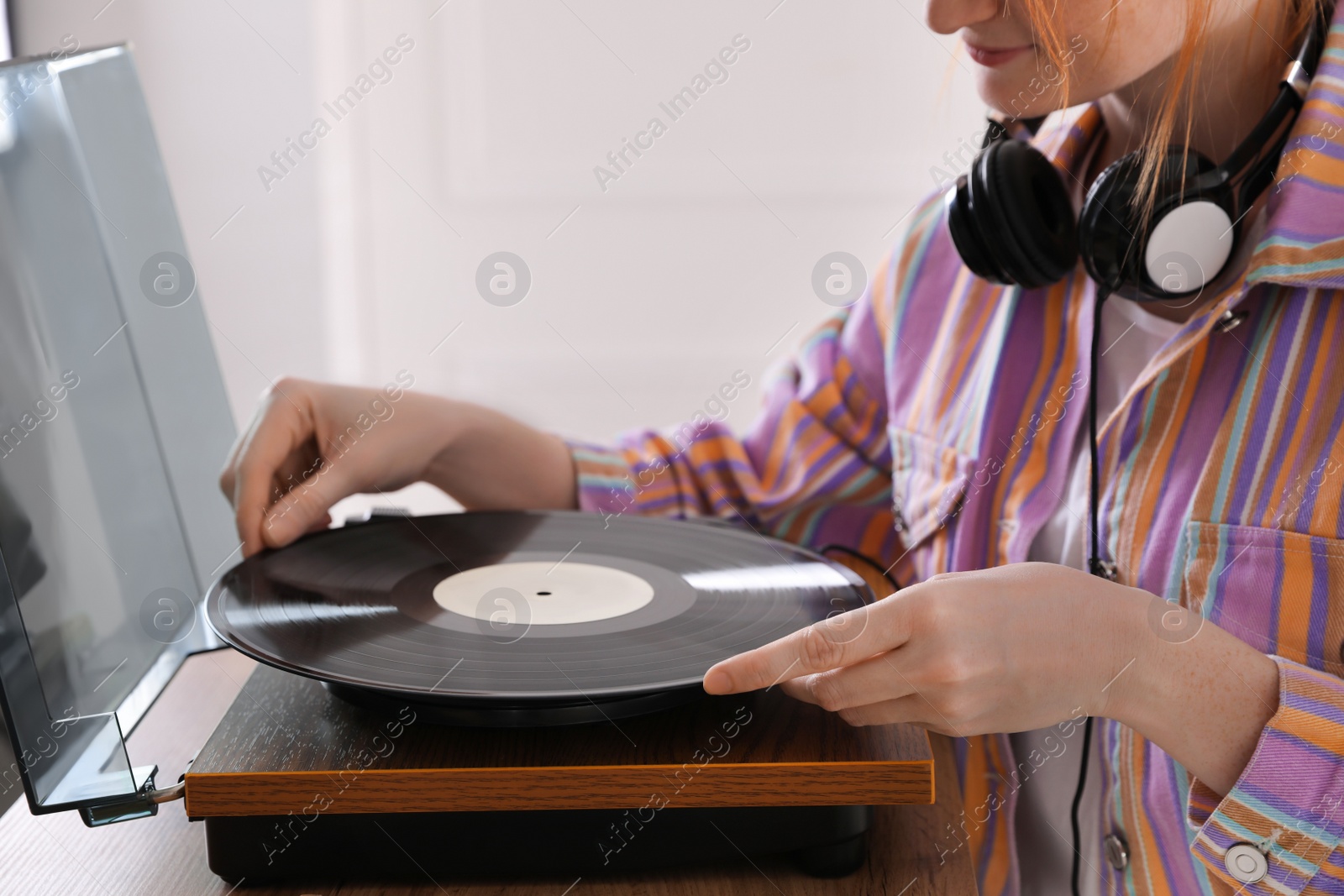 Photo of Young woman using turntable at home, closeup