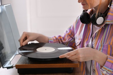 Photo of Young woman using turntable at home, closeup