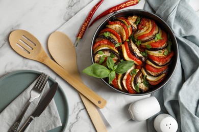 Photo of Delicious ratatouille, chili peppers and cutlery on white marble table, flat lay