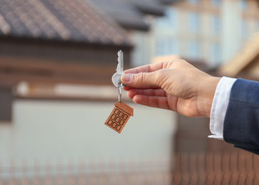 Real estate agent holding key outdoors, closeup