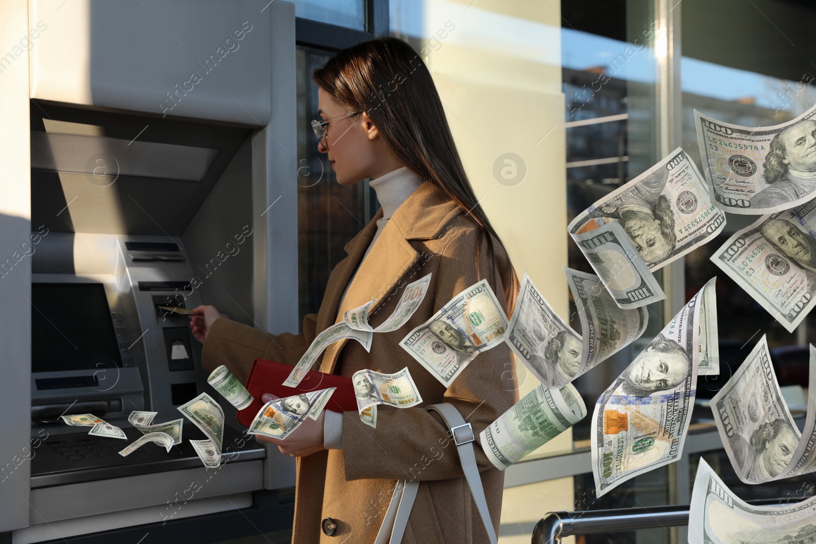 Image of Woman using cash machine and flying money outdoors