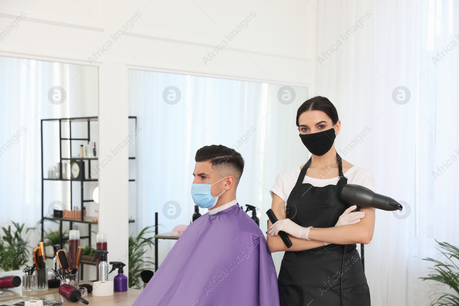 Photo of Professional stylist working with client in salon. Hairdressing services during Coronavirus quarantine