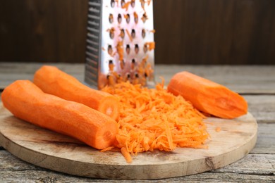 Photo of Cooking delicious sauerkraut soup. Fresh chopped carrot on wooden table, closeup