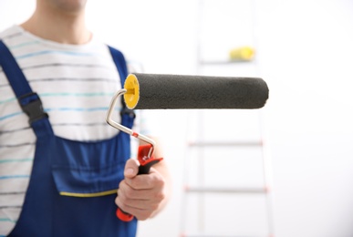 Photo of Young decorator with paint roller in room