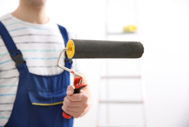 Young decorator with paint roller in room