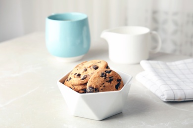 Photo of Bowl with tasty chocolate chip cookies on table