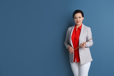 Portrait of female teacher with pointer on color background