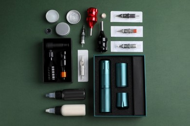 Flat lay composition with tattoo equipment on dark green background