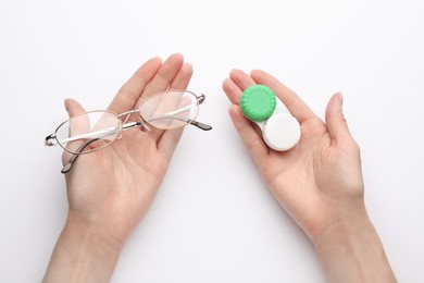 Woman holding case with contact lenses and glasses on white background, top view