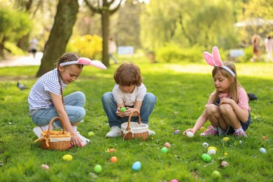 Photo of Easter celebration. Cute little children hunting eggs outdoors