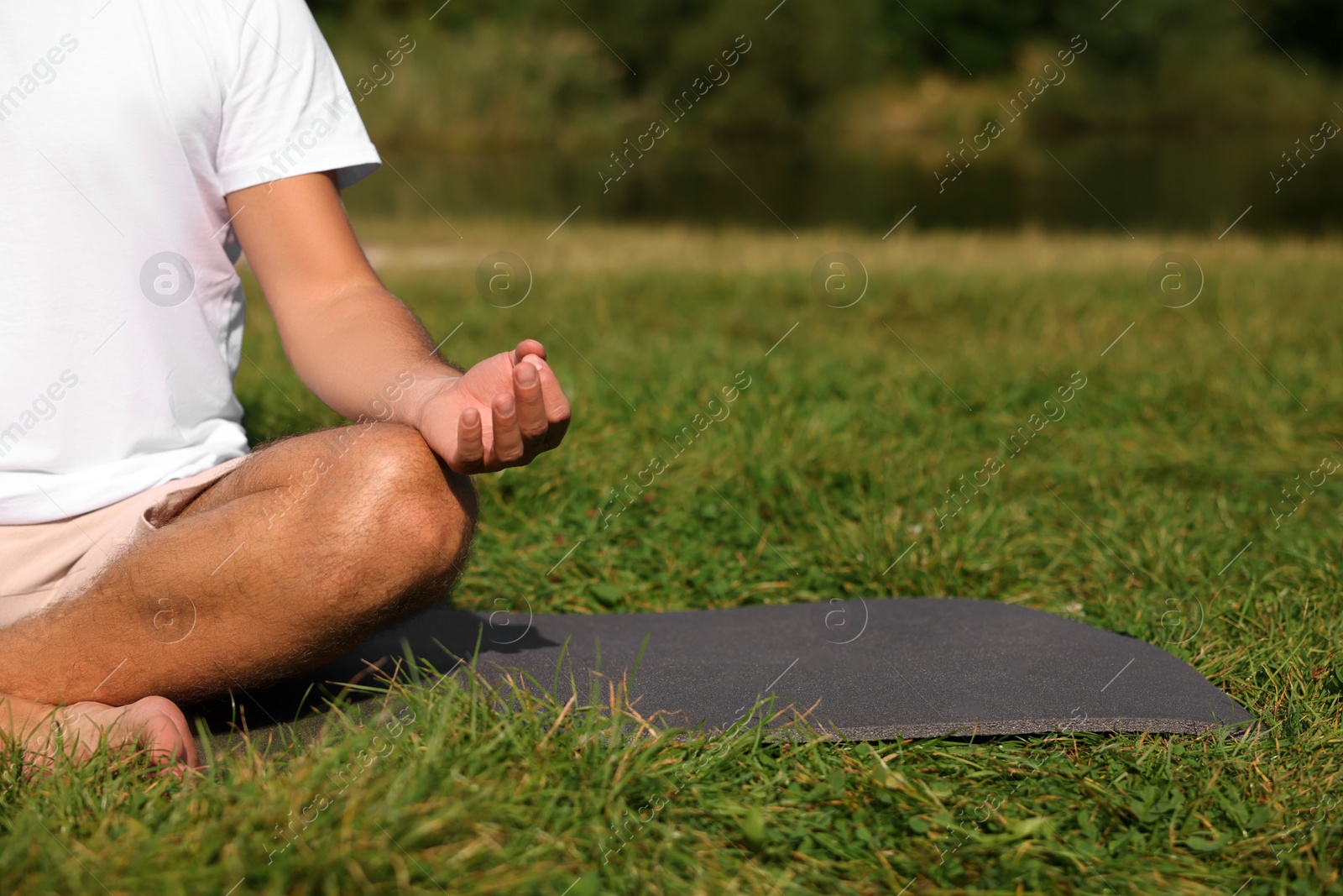 Photo of Man practicing yoga on mat outdoors, closeup and space for text. Lotus pose