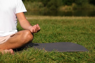 Man practicing yoga on mat outdoors, closeup and space for text. Lotus pose
