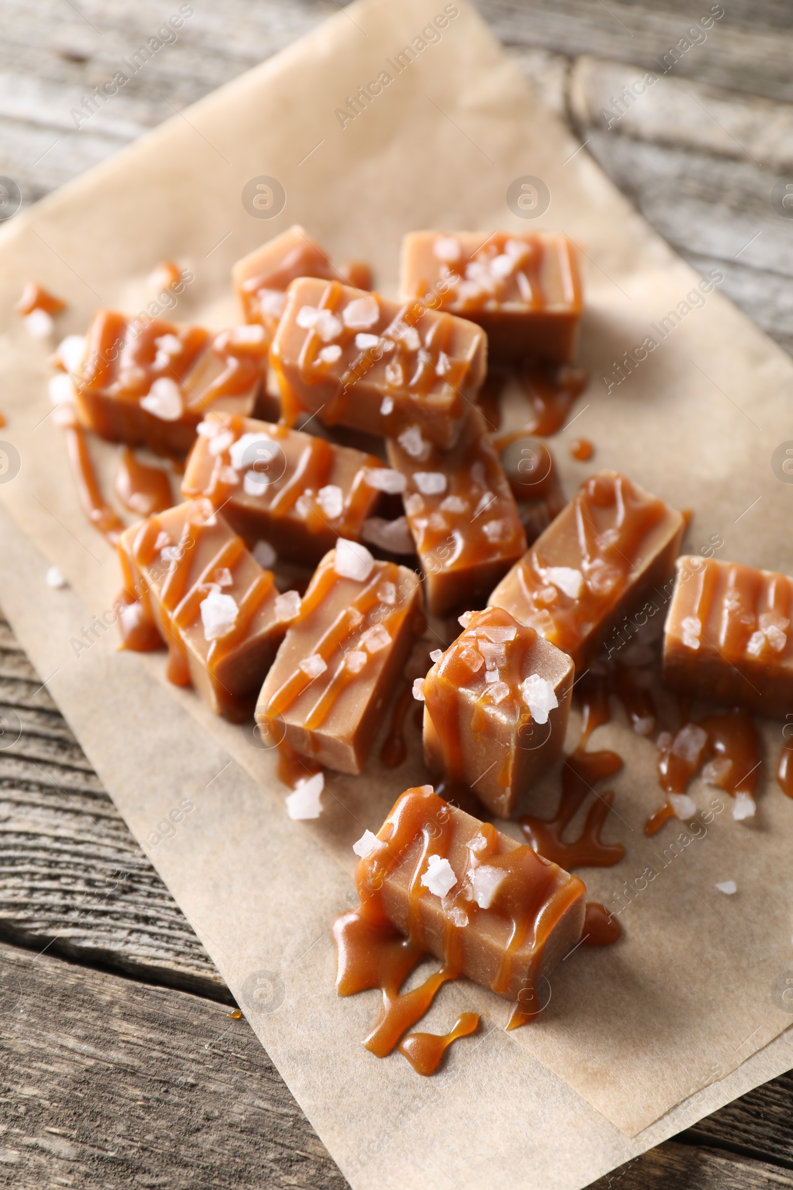 Photo of Yummy candies with caramel sauce and sea salt on wooden table