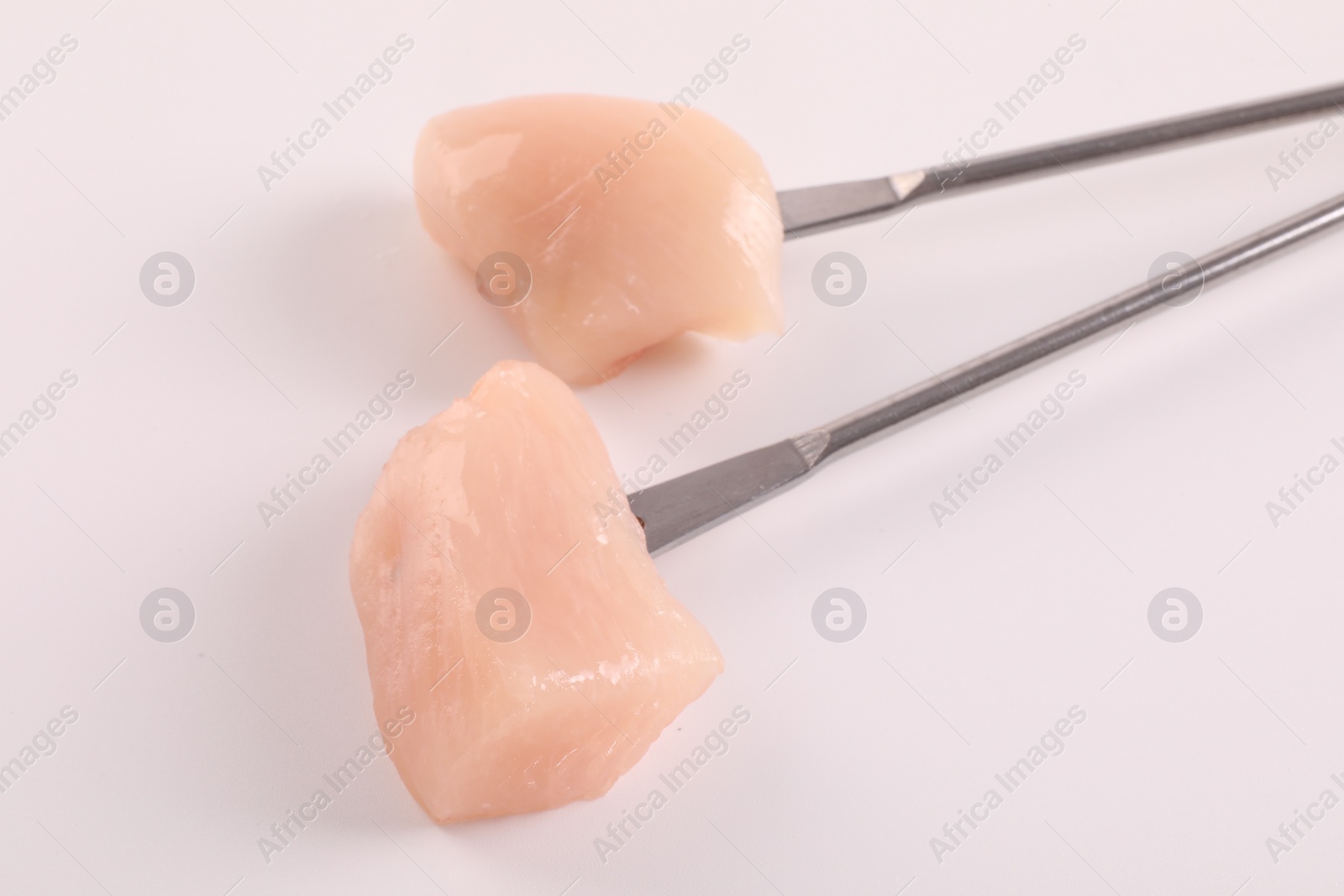 Photo of Fondue forks with pieces of raw meat isolated on white