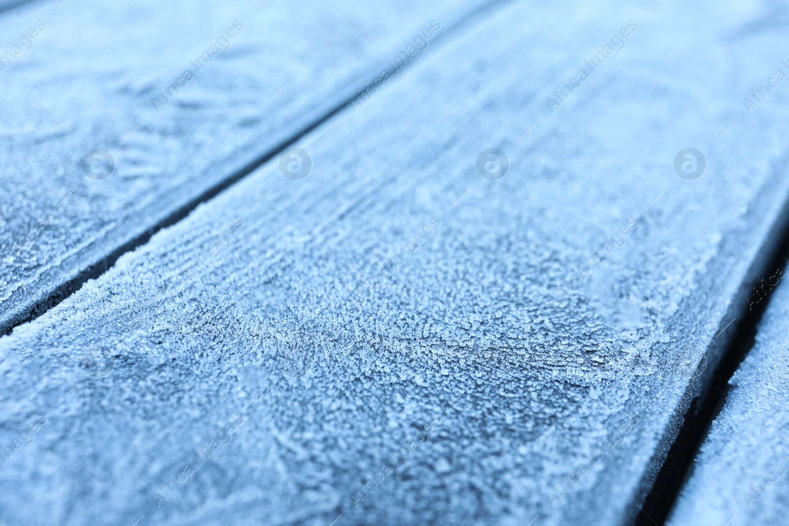 Photo of Beautiful hoarfrost on wooden surface, closeup view