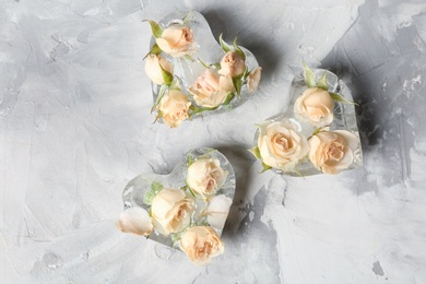 Heart shaped ice cubes with roses on grey background, flat lay composition