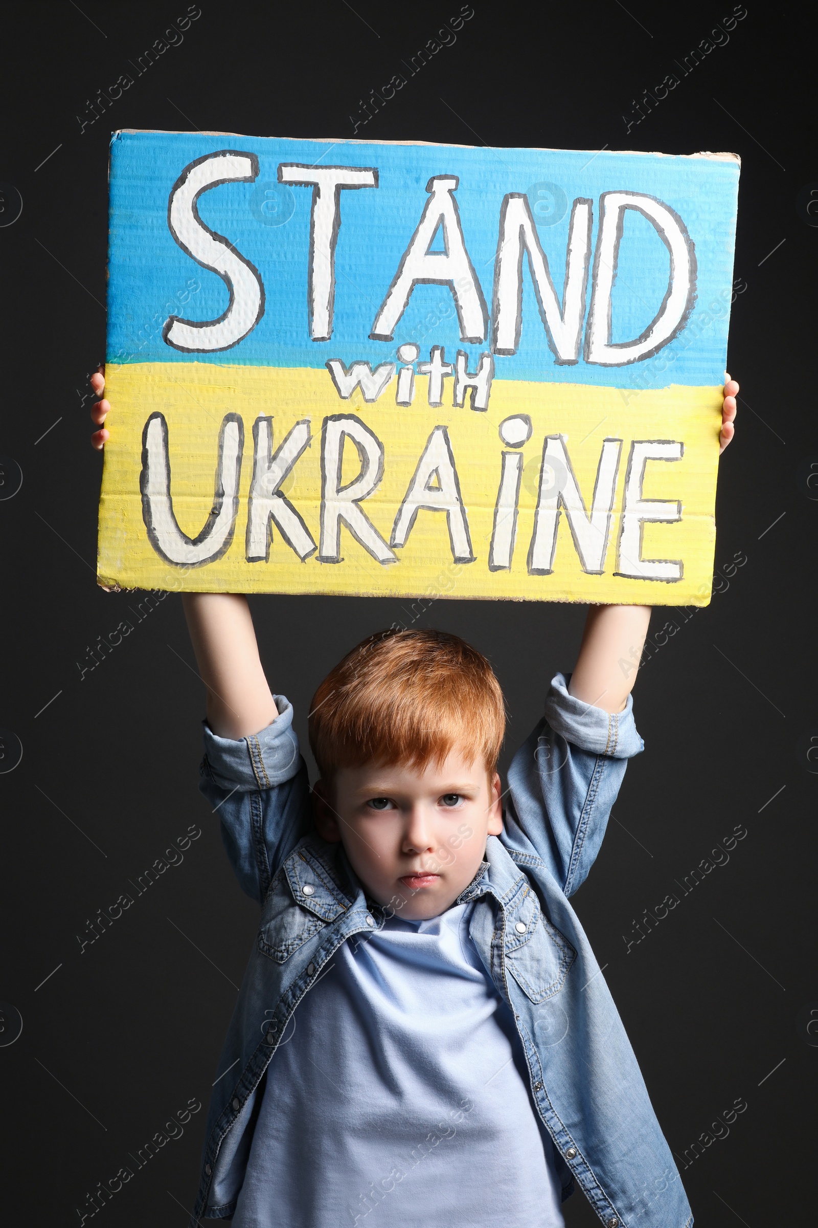 Photo of Boy holding poster Stand with Ukraine against black background