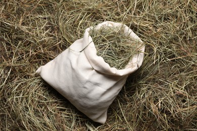 Photo of Dried hay in burlap sack on wooden table, top view