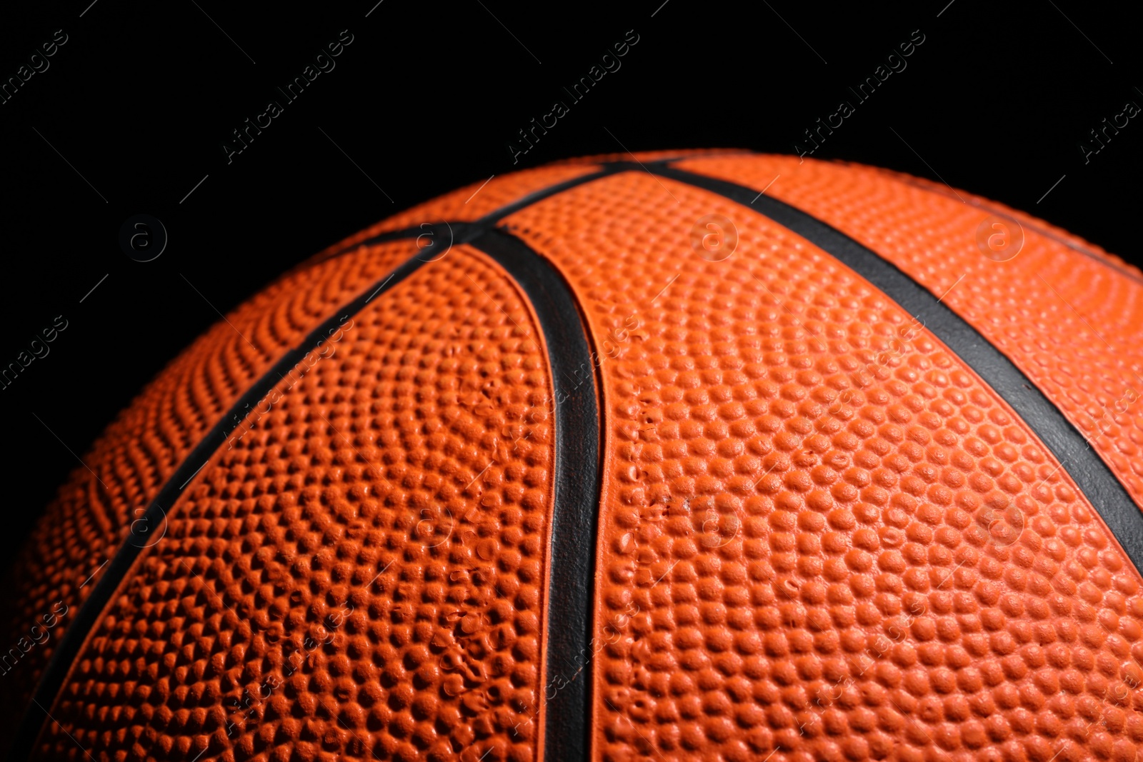 Photo of Orange basketball ball on black background, closeup