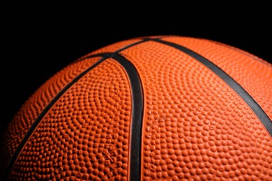 Orange basketball ball on black background, closeup