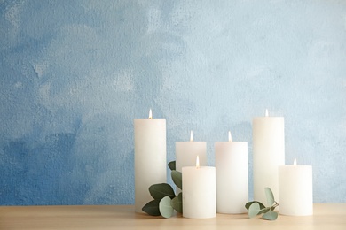 Photo of Composition with burning candles on table against color background. Space for text