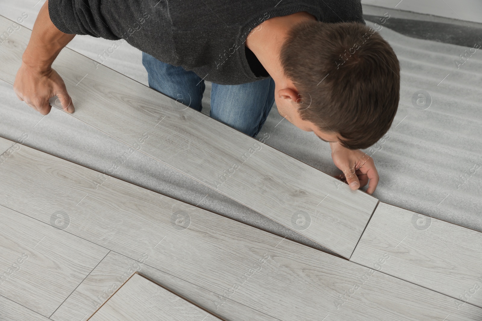 Photo of Worker installing new laminate flooring in room, closeup