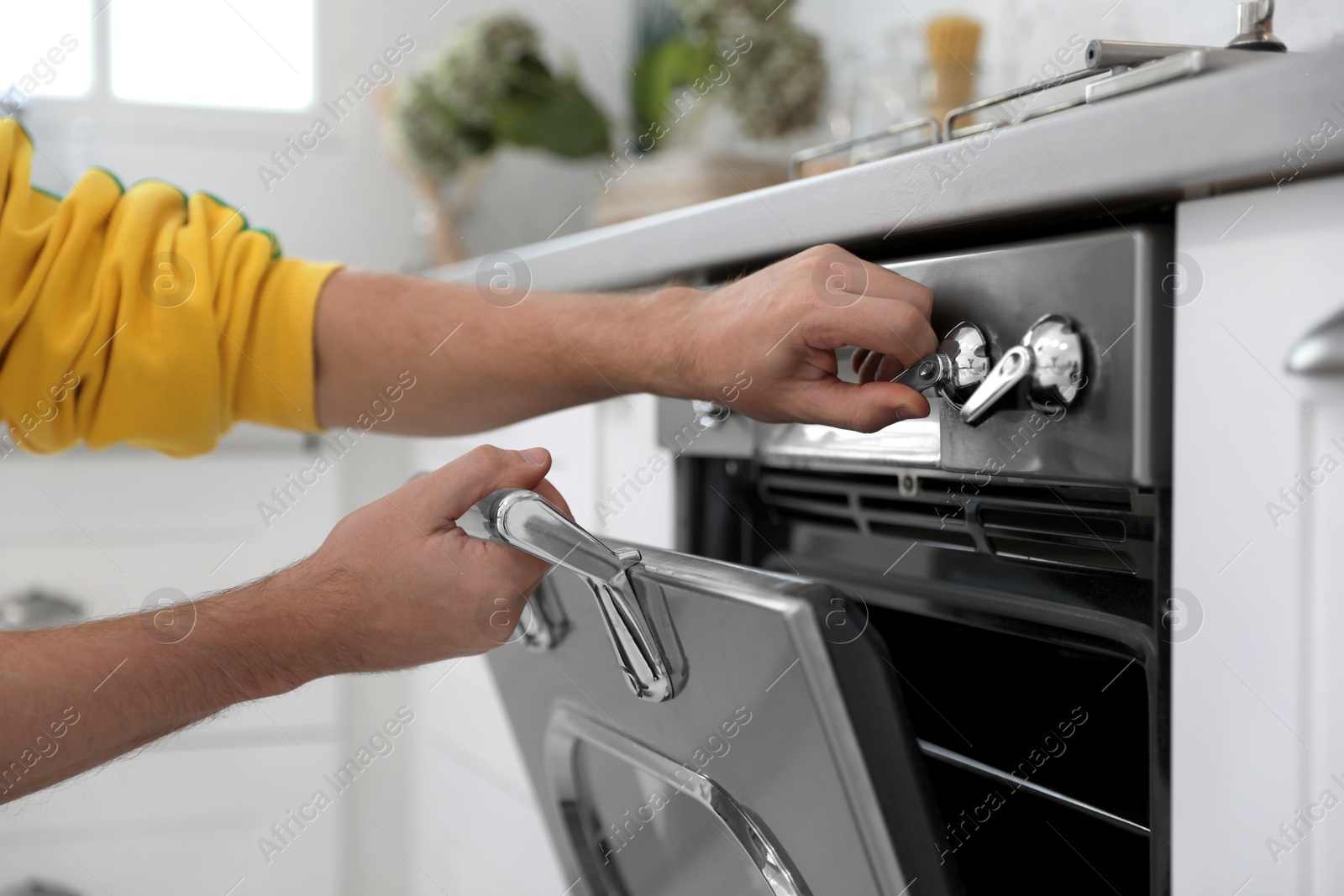 Photo of Man using modern oven in kitchen, closeup