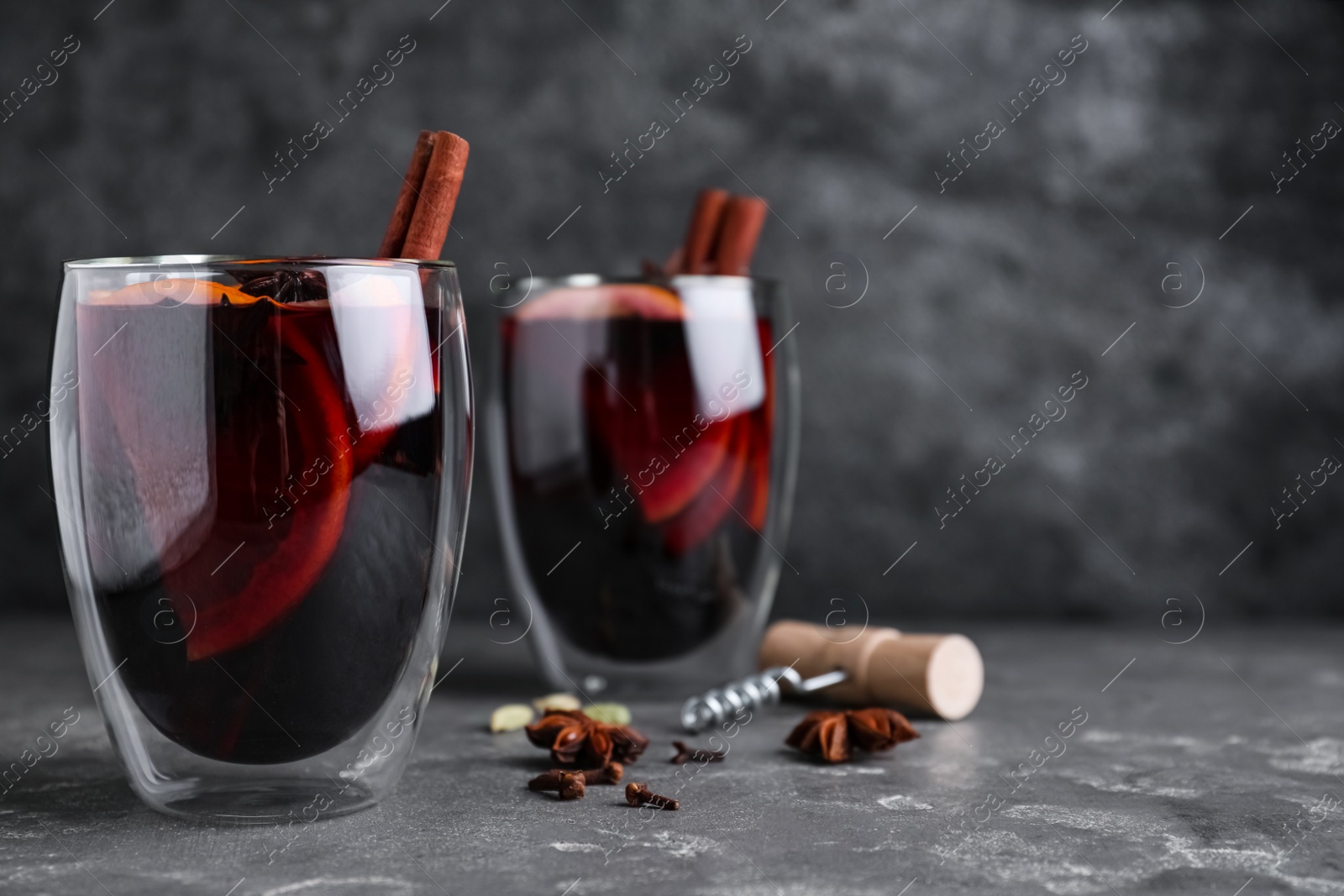 Photo of Aromatic mulled wine on grey table. Space for text