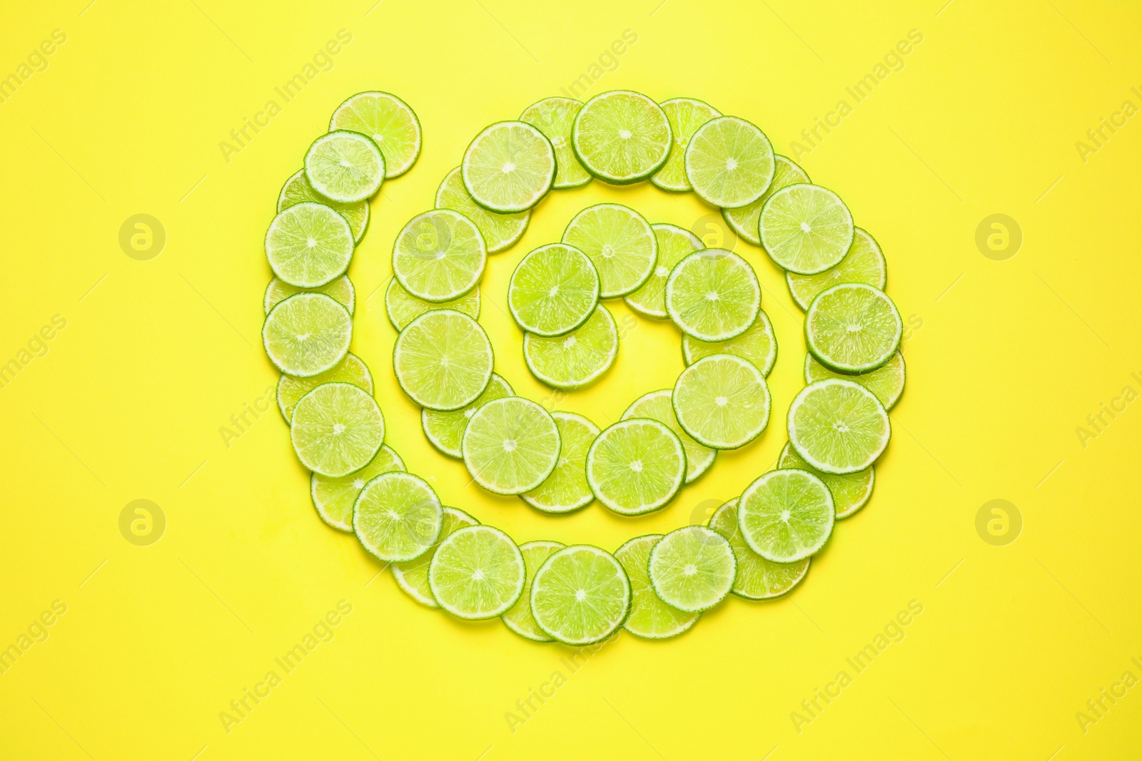 Photo of Juicy fresh lime slices on yellow background, flat lay