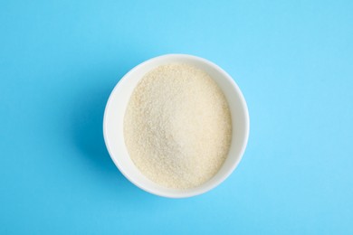 Gelatin powder in bowl on light blue background, top view