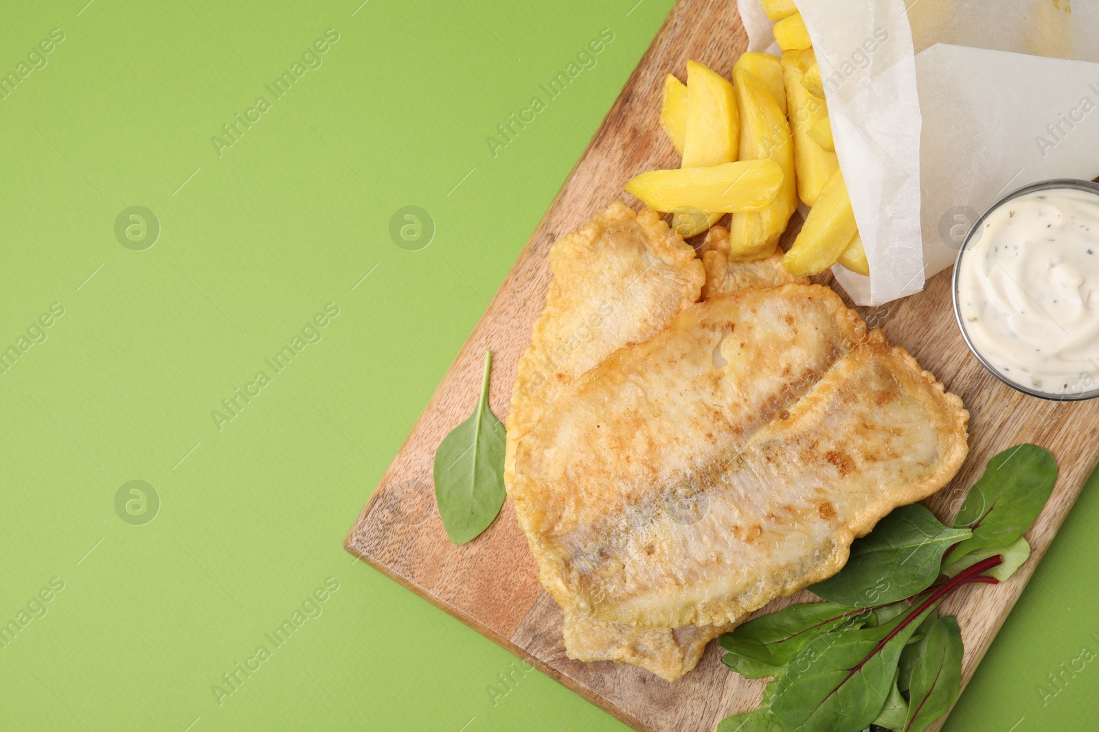 Photo of Delicious fish and chips with tasty sauce and mangold on green table, top view. Space for text