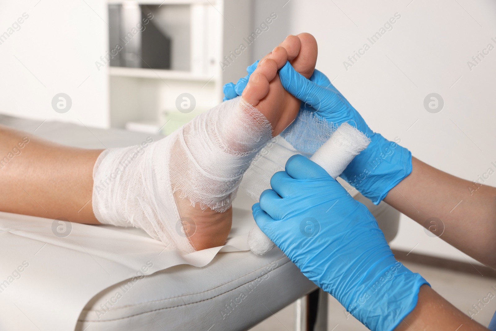 Photo of Doctor applying bandage onto patient's foot in hospital, closeup