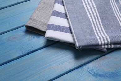 Photo of Different kitchen towels on blue wooden table. Space for text