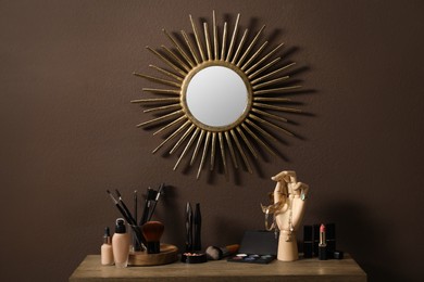 Photo of Stylish round mirror hanging above dressing table with cosmetic products and jewelry