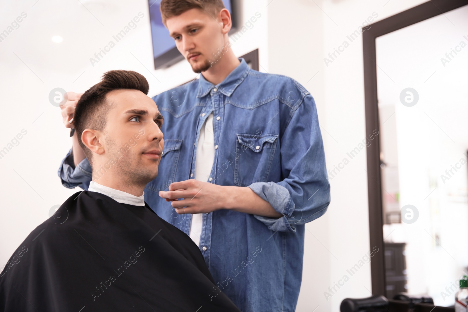 Photo of Professional barber working with client in hairdressing salon. Hipster fashion