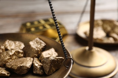 Photo of Scale pan with gold lumps on table, closeup. Space for text