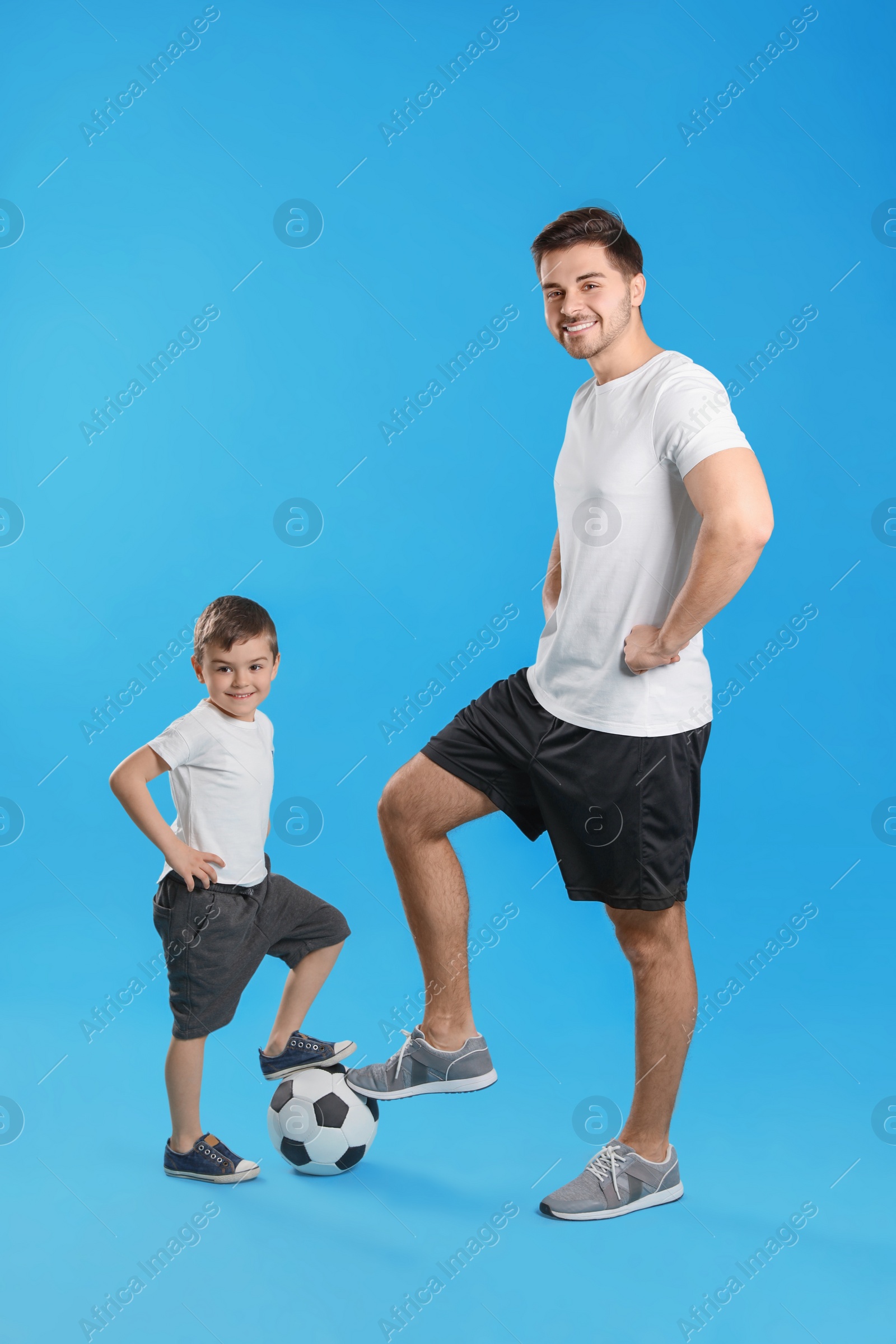 Photo of Portrait of dad and his son with soccer ball on color background