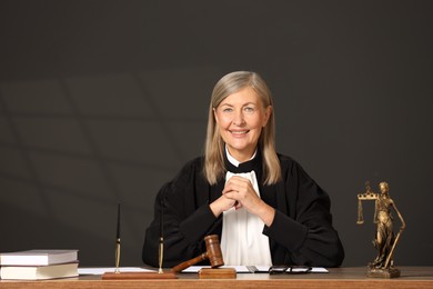 Portrait of smiling judge in court dress at table indoors. Space for text