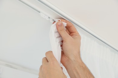 Worker hanging window curtain, closeup of hands