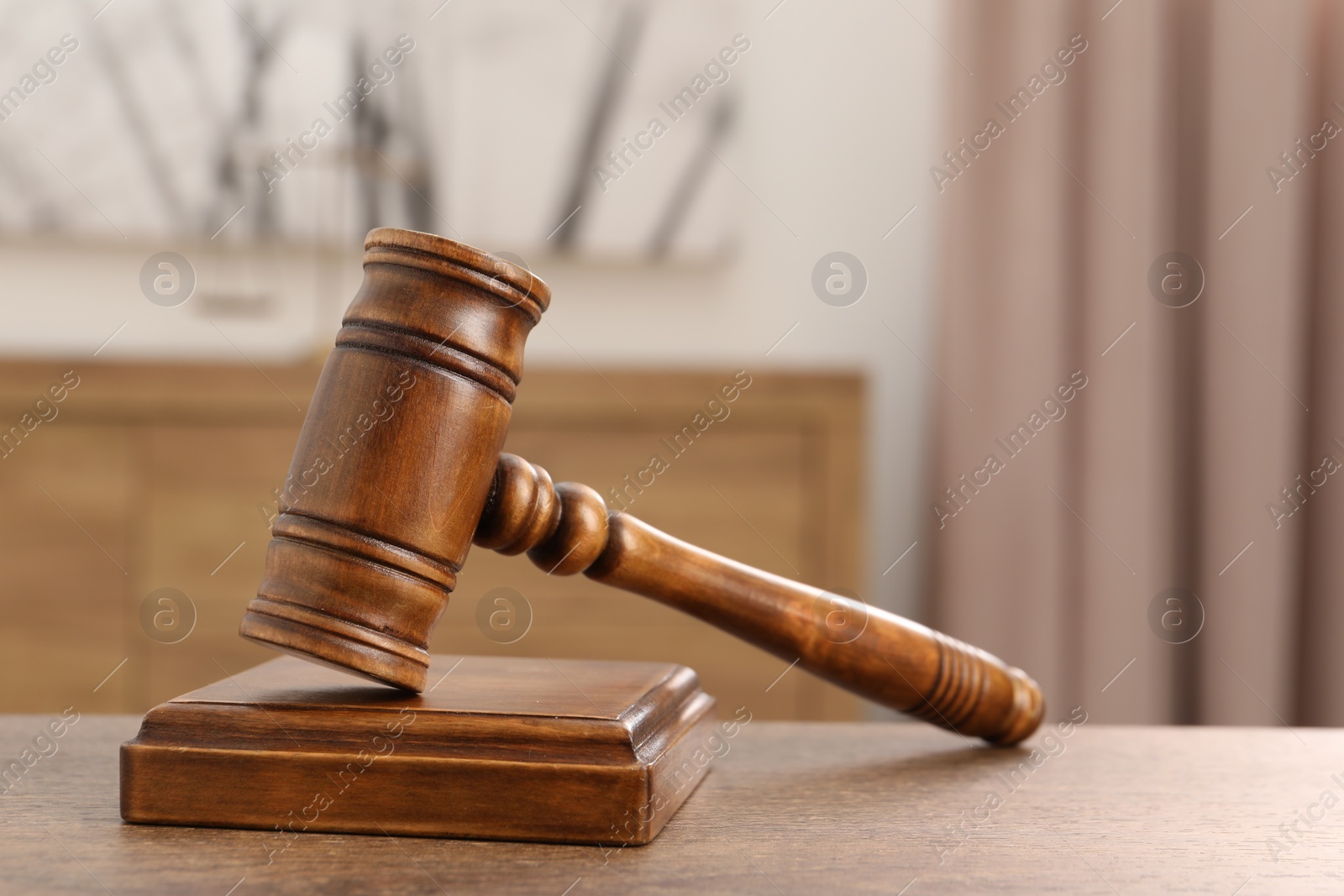 Photo of Wooden gavel and sound block on table indoors, closeup