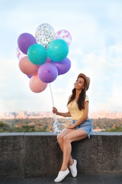 Photo of Cheerful young woman with color balloons outdoors