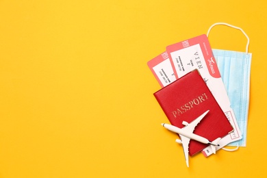 Photo of Flat lay composition with passport and protective mask on yellow background, space for text. Travel during quarantine